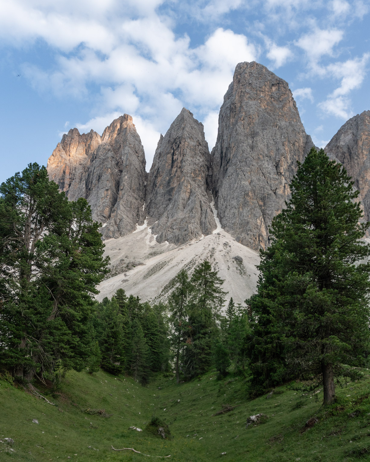 Under four pinacle-like mountains a little dip between conifers, perhaps carved by glaciers?